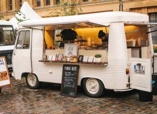 Berlin, October 1, 2017: White cozy small mini bus food market with snacks and coffee and two sellers